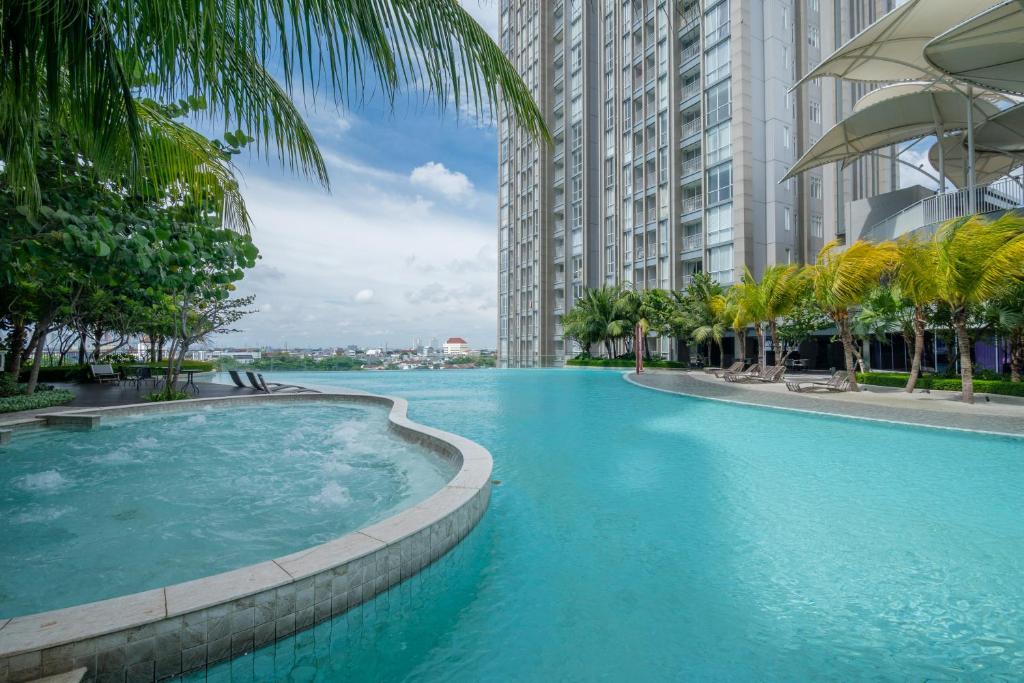 a large swimming pool with palm trees and buildings at Morich Penthouse Jakarta in Jakarta