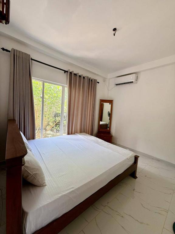 a bedroom with a large bed and a window at Blue Wave Holiday Villa in Weligama