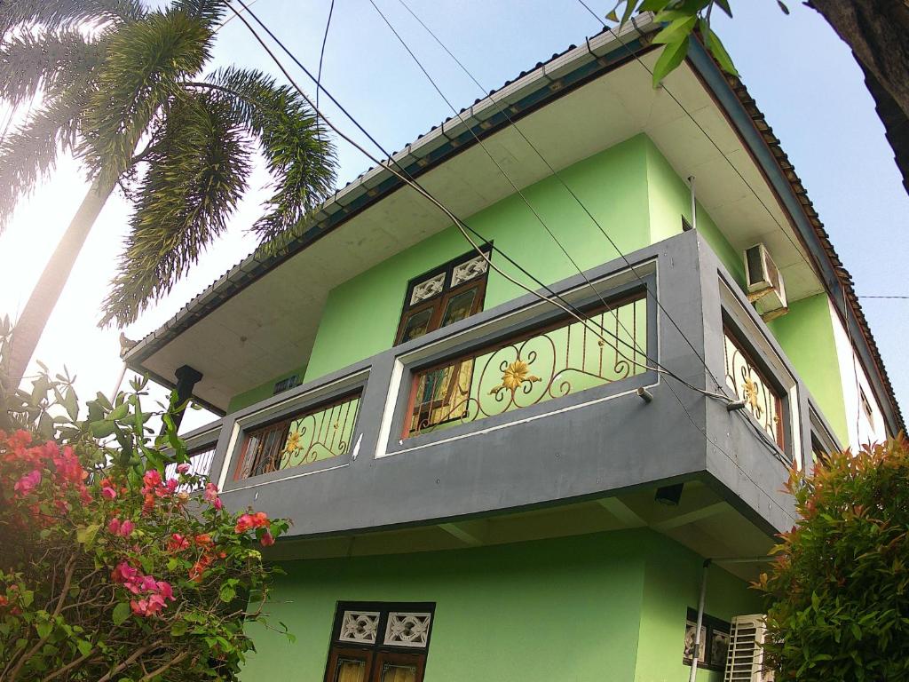 a green house with a balcony on top of it at Taba Yama Trip & Homestay in Ketapang