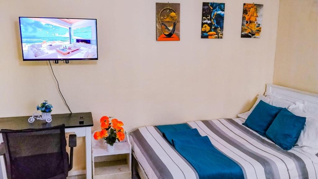 a bedroom with a bed and a tv on the wall at Des Homes in Nairobi