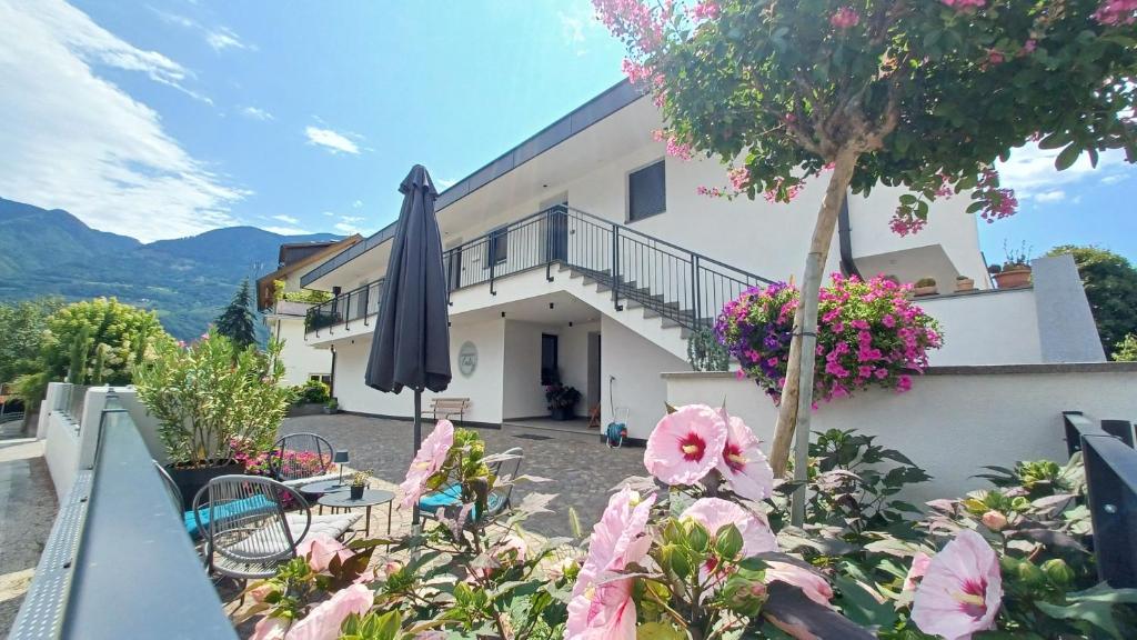 a villa with a balcony with a umbrella and flowers at Bike Apartments Curti - Abendrot in Laives