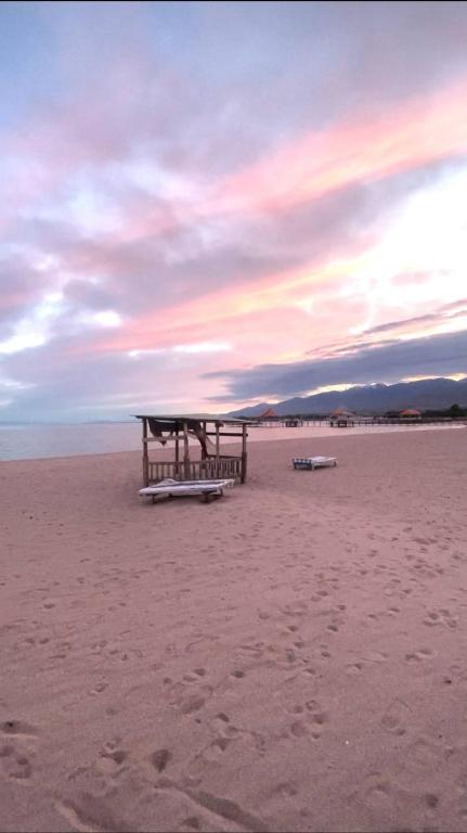 a picnic table on a beach with a cloudy sky at Diamond resort in Bosteri
