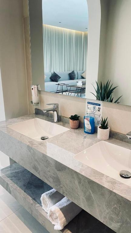 a bathroom with two sinks and a large mirror at بالم هيلز Palm Hills in Baljurashi