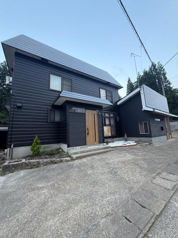 a black house with a door and a driveway at Kuro House Myoko in Myoko