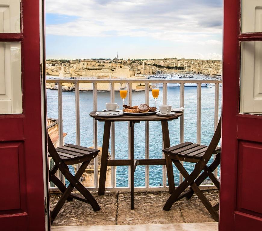 a table with two glasses of wine on a balcony at Luciano Al Porto Boutique in Valletta