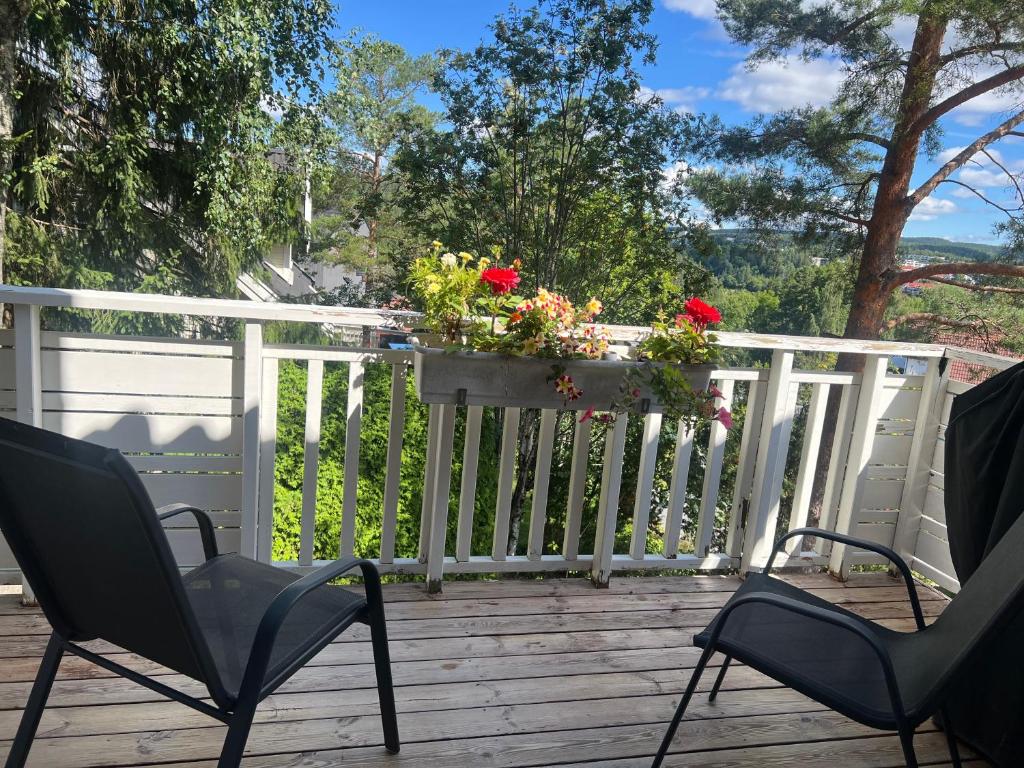 two chairs on a deck with flowers on a fence at 3rd Floor Living Space with Shared Kitchen in Oslo