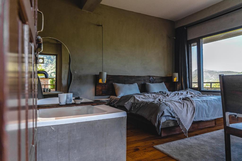 a bedroom with a bed and a bath tub next to a sink at THHPSOCIETY - Exstacy stays & cafe - Your Romantic & Cozy Getaway - Mountain view , Hot tub , Parking - MUKTESHWAR in Mukteshwar