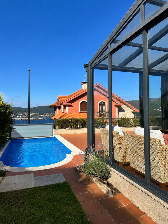 a house with a swimming pool in front of a house at Xanela da Ría in Quenje