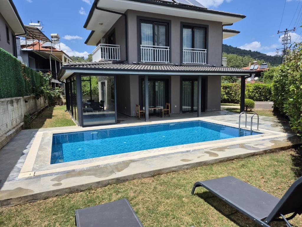 a villa with a swimming pool in front of a house at Villa Kaya Maris Göcek in Fethiye