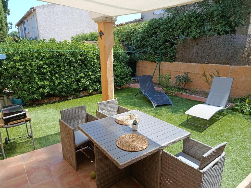 a patio with a table and chairs in a yard at Hébergement Climatisée Cogolin in Cogolin