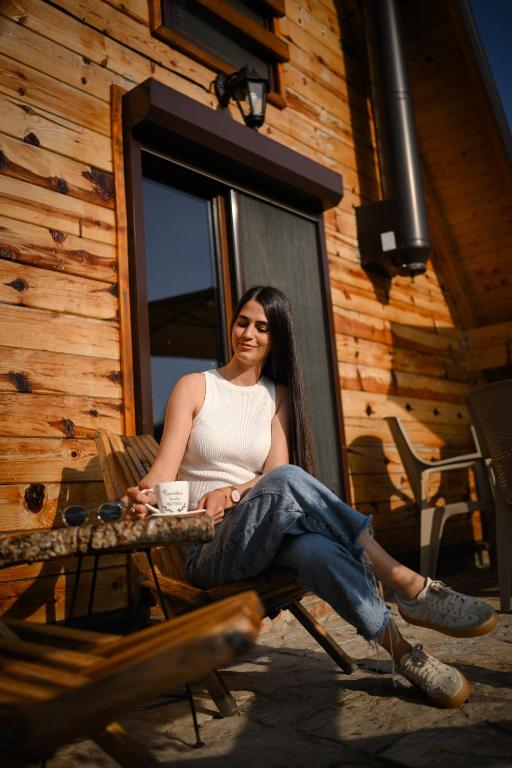 a woman sitting on a chair with a cup of coffee at Planinska kuća Isiteo in Kremna