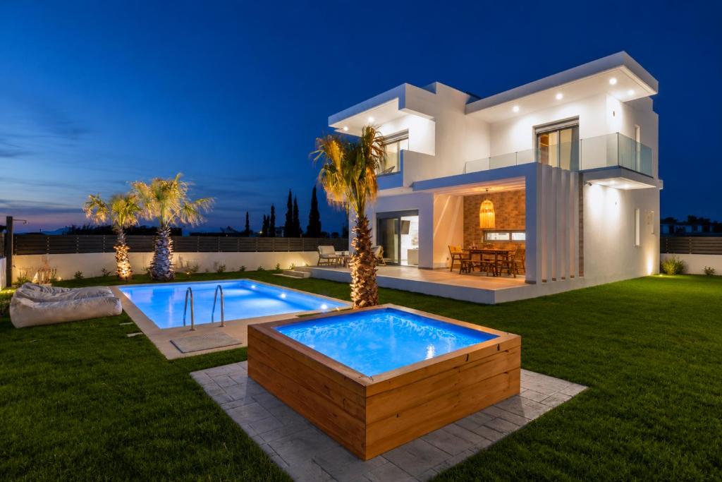 a villa with a swimming pool in front of a house at Martini Villas in Kremasti