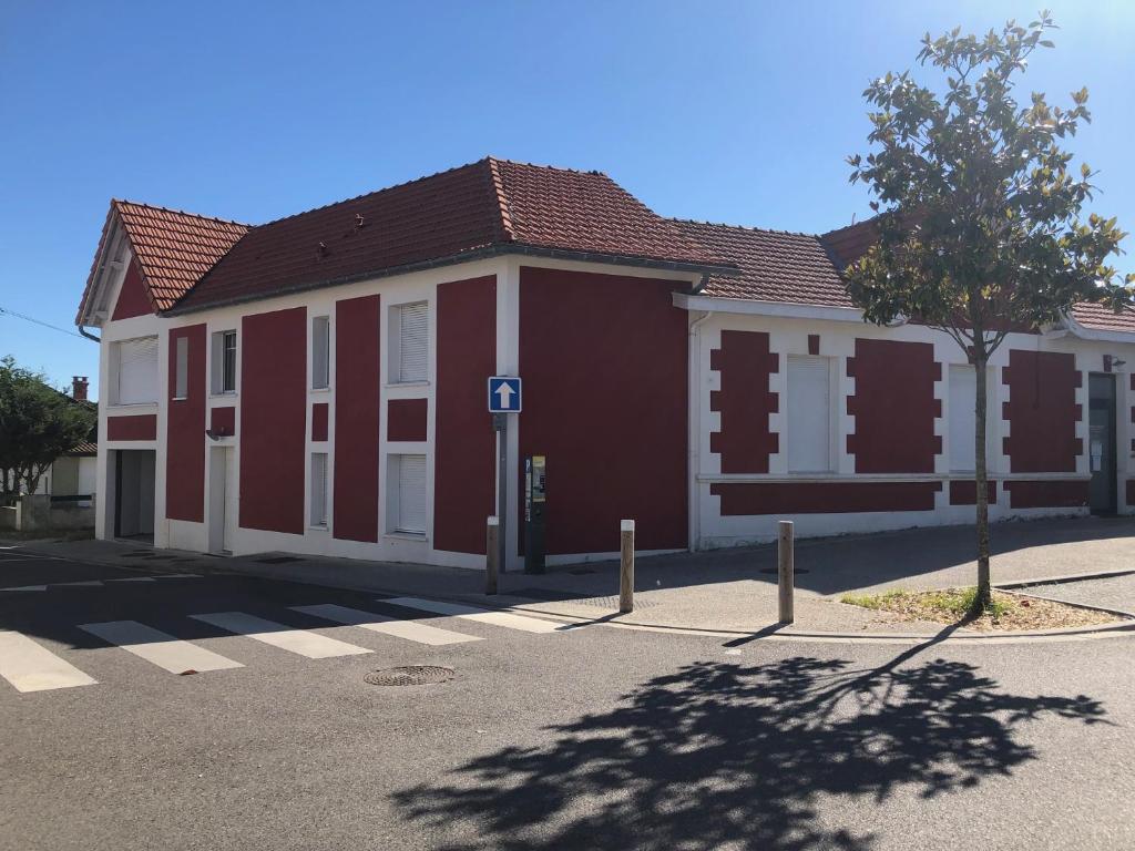 a red and white building with a tree in front of it at Villa Maude & Jean in Lacanau-Océan