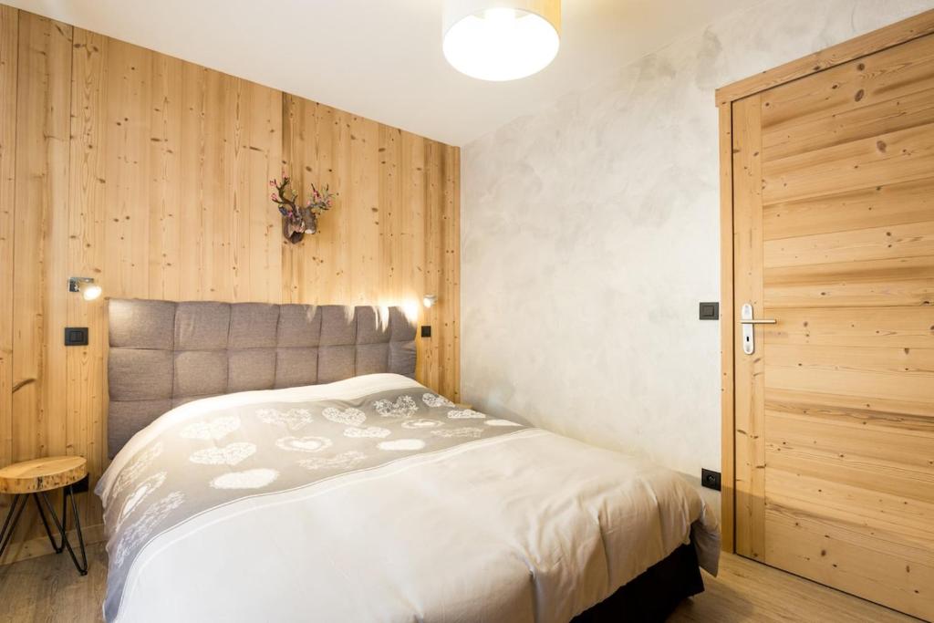 a bedroom with a bed and a wooden wall at Cozy chaleett on SLOPES in Crest-Voland