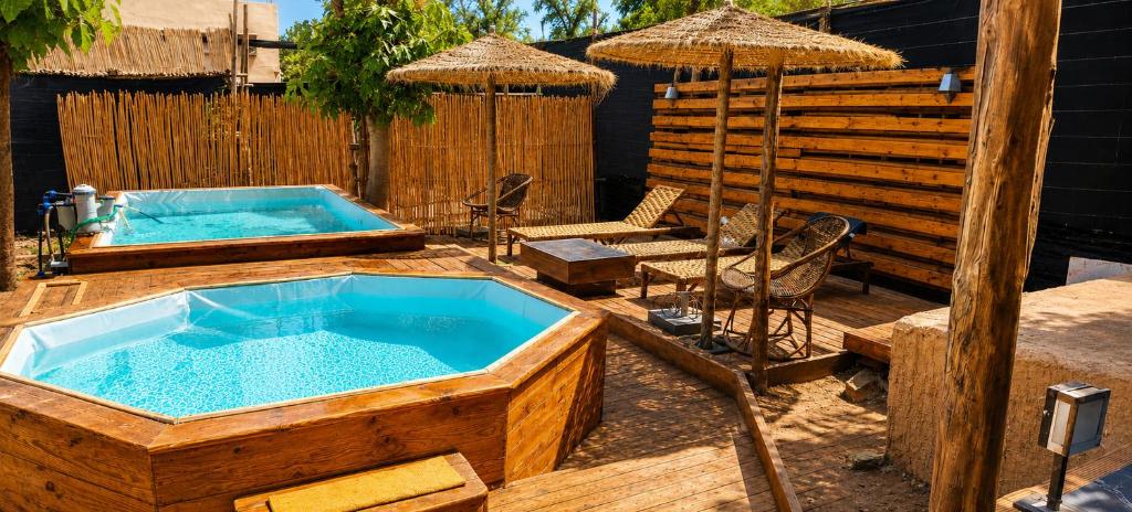 a hot tub in a wooden deck with an umbrella at Appartement Riad à Taroudant Piscine Privée & Grand Jardin, Séjour Unique in Taroudant