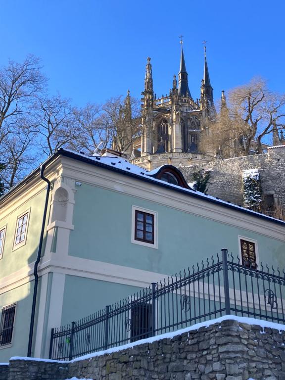 a white building with a fence in front of a castle at Boutique hotel Pod Barborou in Kutná Hora