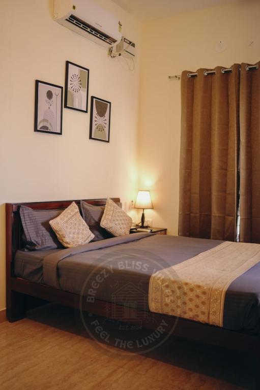 a bedroom with a bed and a lamp on a table at Breezy Classy Villa Mahabalipuram in Kelambākkam