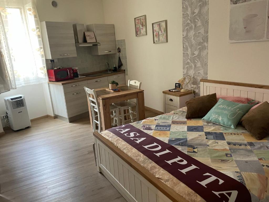 a bedroom with a large bed and a kitchen at La casa di Pi Ta in Sassari