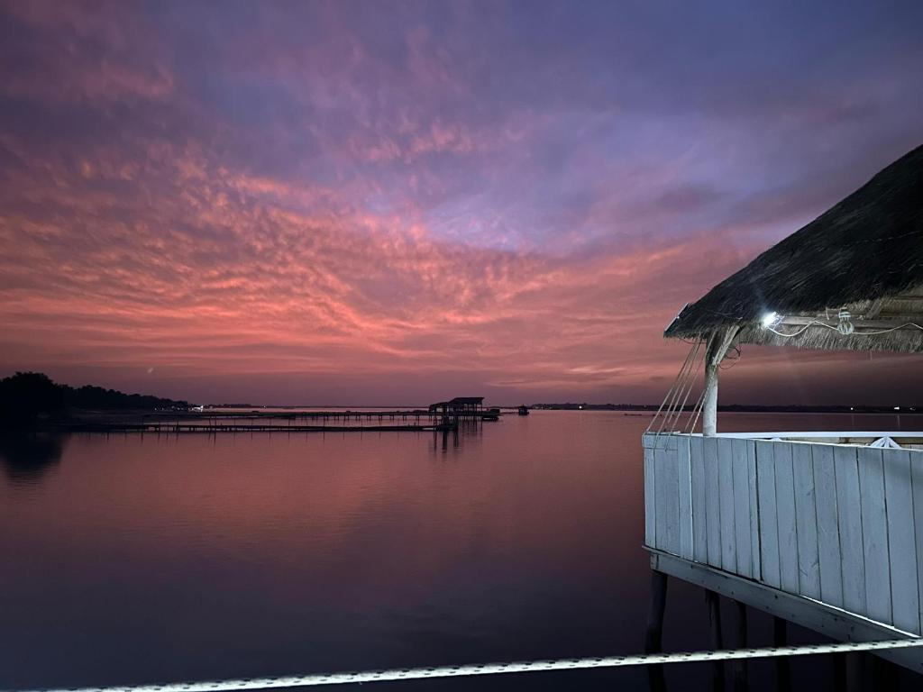 a dock on a body of water with a sunset at Timonier Ecolodge in Mar Lodj