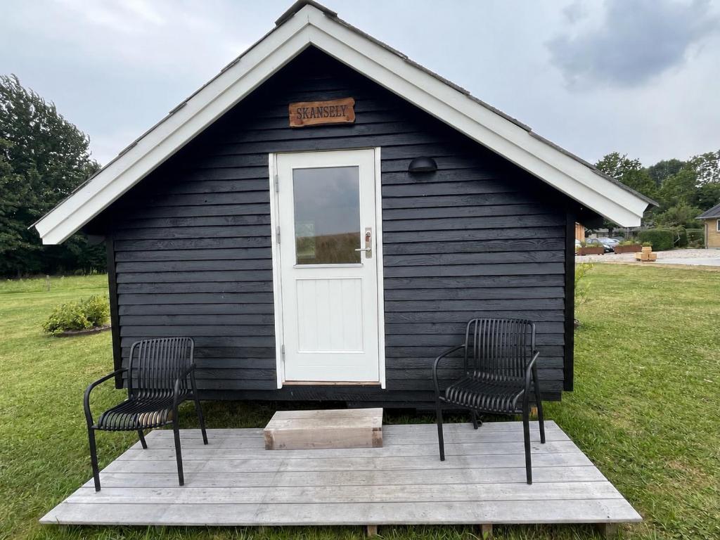 a black house with two chairs in front of it at Skansely in Sønderborg