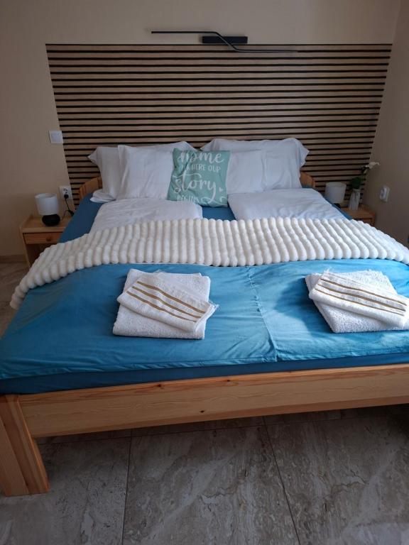 a large bed with blue sheets and pillows on it at Szabó Vendégház in Bükkszék