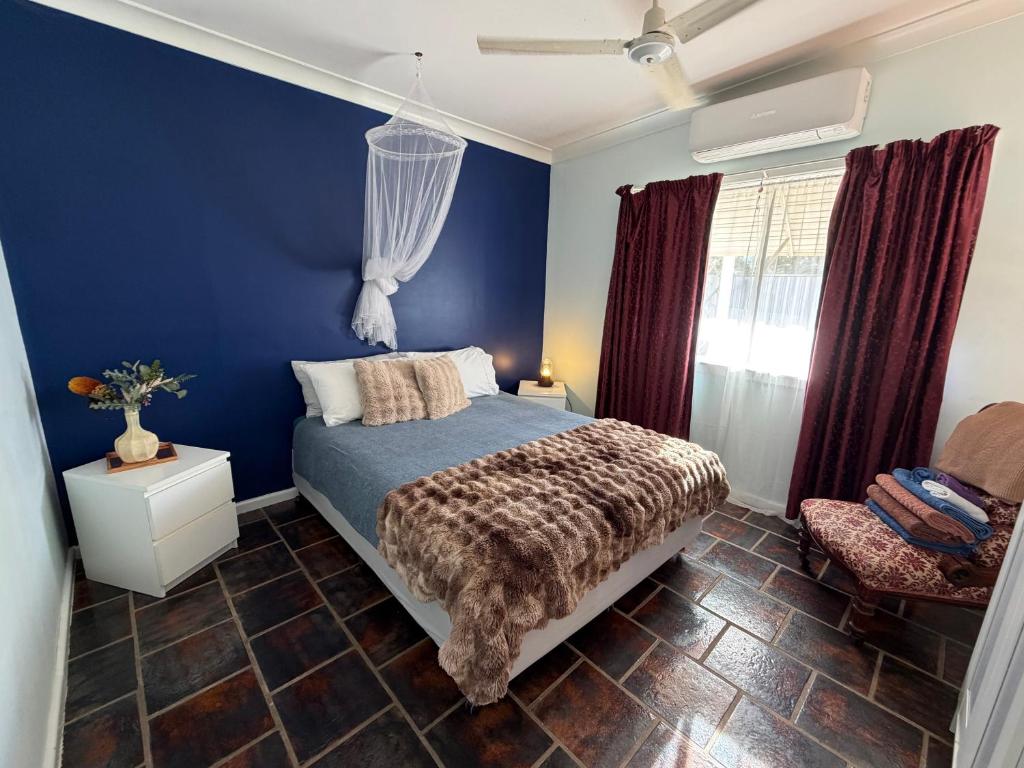 a blue bedroom with a bed and a chair at Opal St Homestay in Lightning Ridge