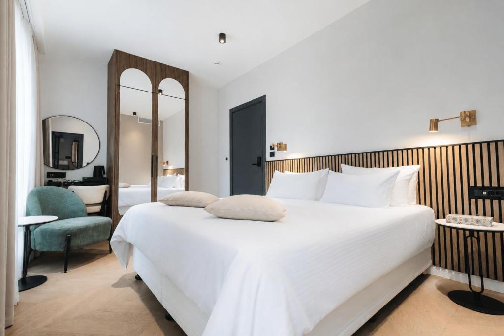 ein Schlafzimmer mit einem großen weißen Bett und einem Stuhl in der Unterkunft Hotel Flaneur in Belgrad