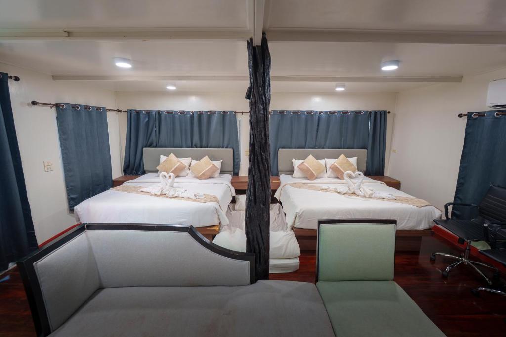 two beds in a room with blue curtains at แพในฝัน รีสอร์ท in Ban Tha Thong Mon