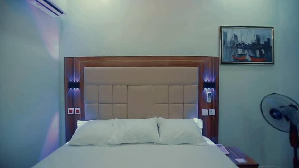 a bedroom with a large bed with a large headboard at Riverleaf Hotels and Suites in Asaba