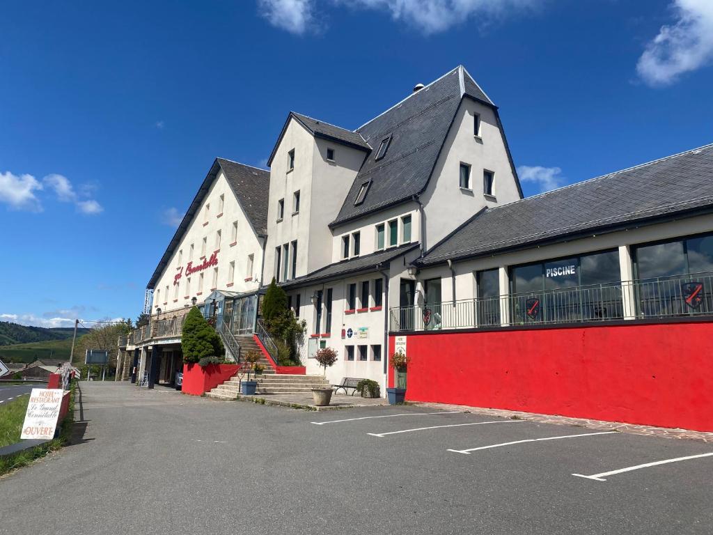 a large white building with a red wall at Le Grand Connétable in Châteauneuf-de-Randon