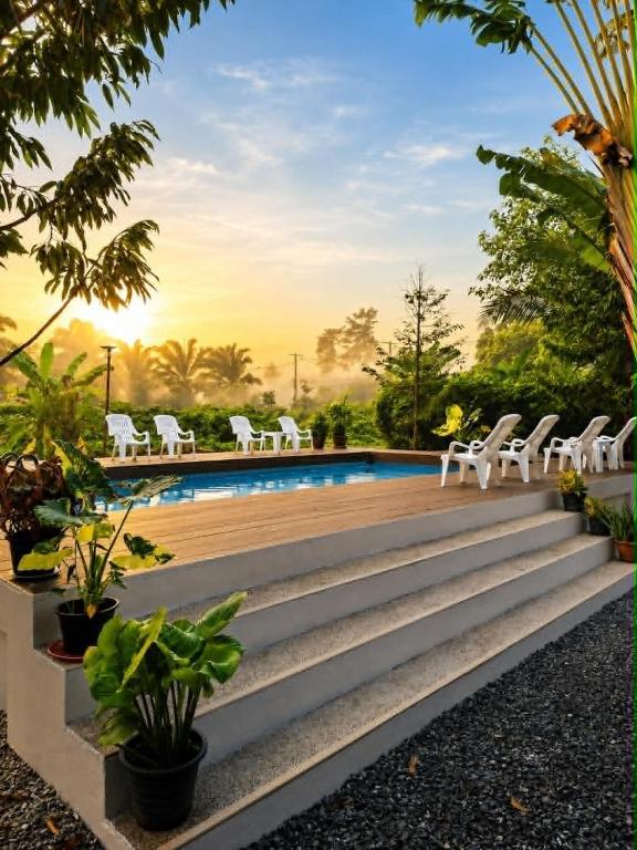 a resort pool with white chairs and trees at Khao Sok Holiday Resort in Khao Sok National Park