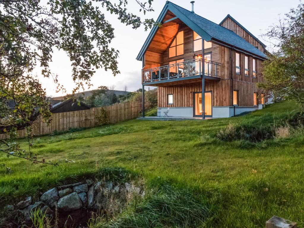 a wooden house on a hill with a yard at Strathspey Lodge in Duthil