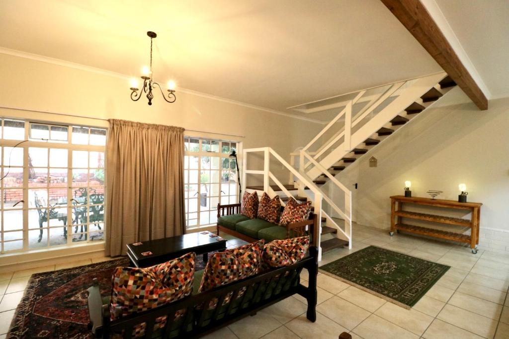 a living room with a couch and a staircase at Cottage on 10th in Gqeberha