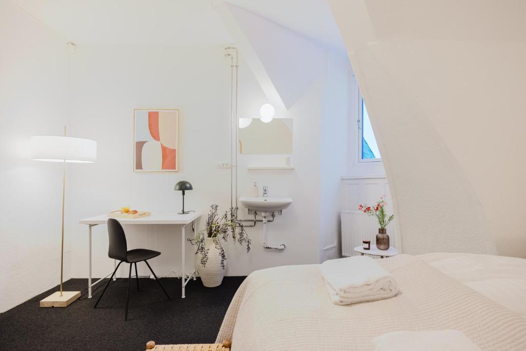 a white room with a bed and a desk and a sink at Nomad Hotel - Frederiksberg in Copenhagen