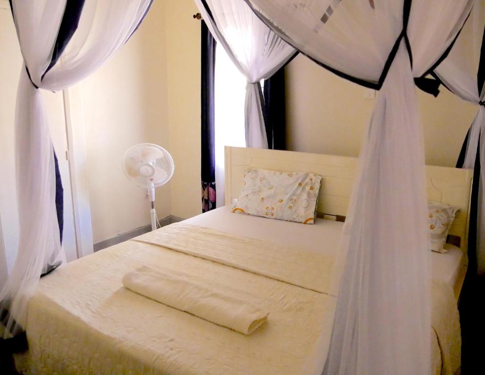une chambre avec un lit blanc à baldaquin dans l'établissement Hotel Acacia City, à Kampala
