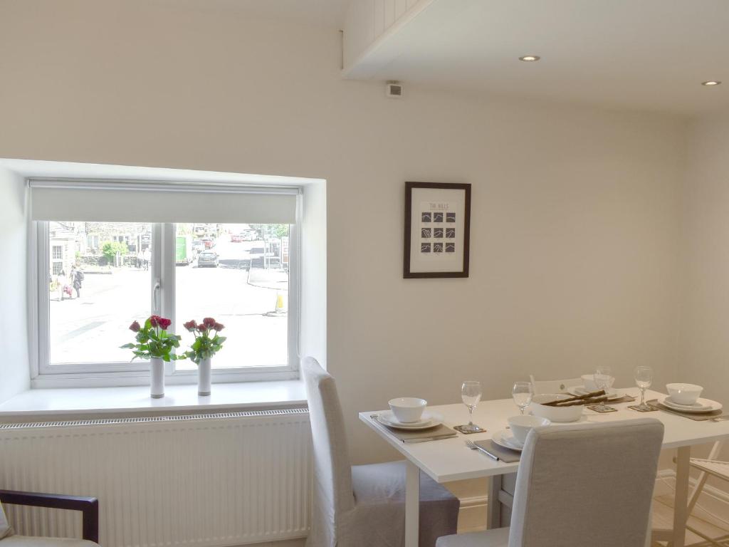 a white dining room with a table and a window at Morton Loft in Hathersage