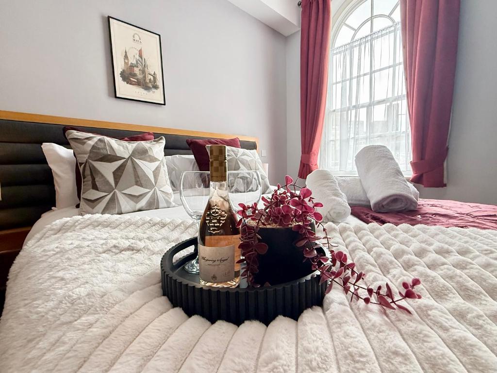 a bed with a bottle of wine and flowers on it at Maya Hotel in Luton