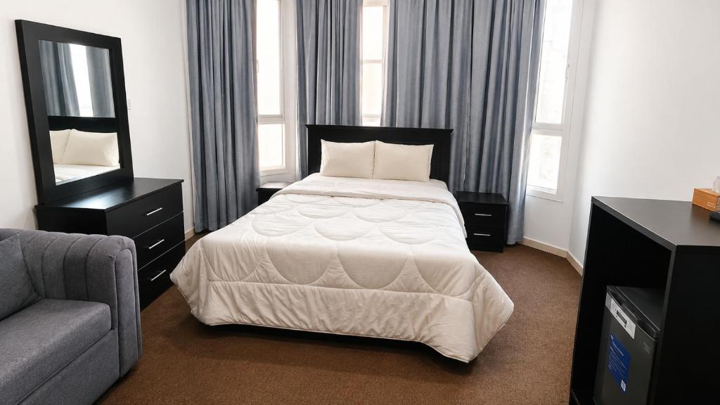 a bedroom with a bed and a couch and a mirror at Khalifa A Apartement V15 in Abu Dhabi