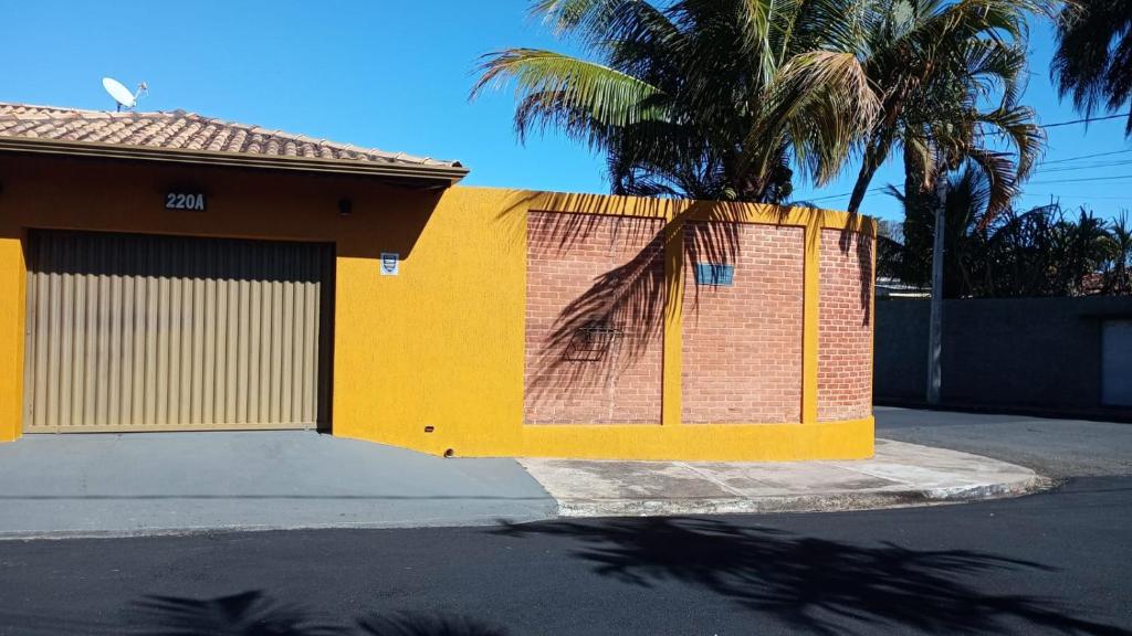 a yellow fence next to a building with a palm tree at Espaço Gozzoli, Cantinho da Nonna in Espirito Santo Do Pinhal