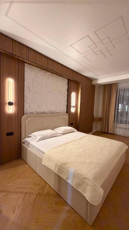 a bedroom with a large white bed with two lights at Capital city in Shymkent