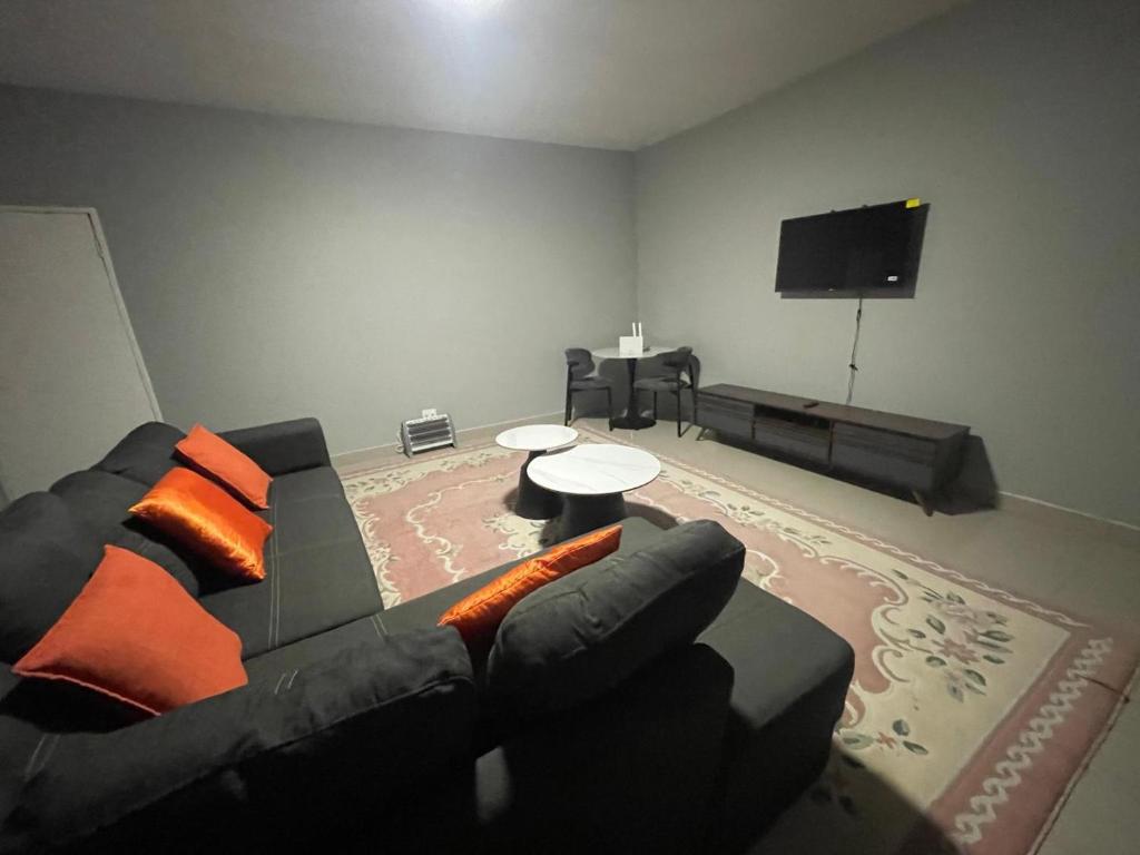 a living room with a black couch and a flat screen tv at Leeba Apartments in Maseru