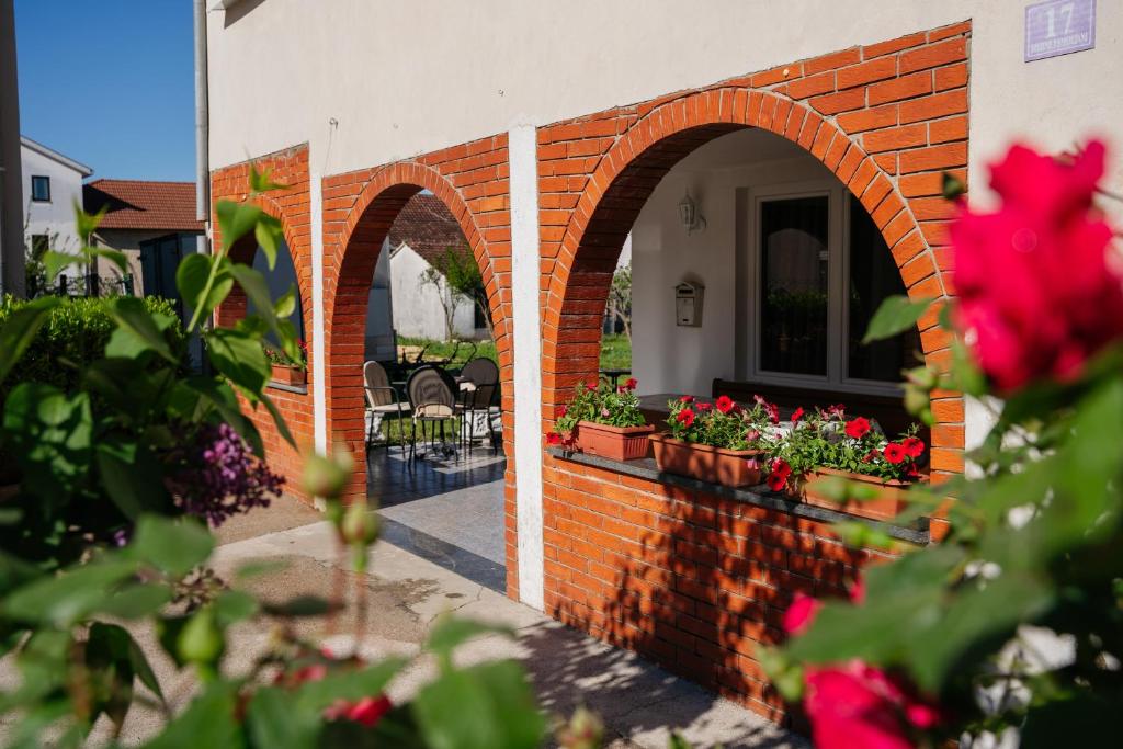 a brick wall with two arches with flowers on it at Sobe Kozina in Međugorje