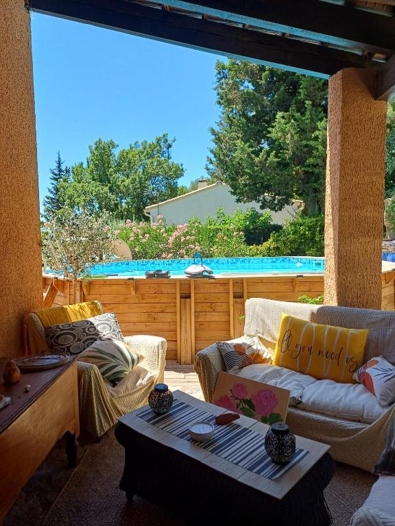 a patio with two couches and a table and a pool at La Parenthèse Provençale in Cabasse