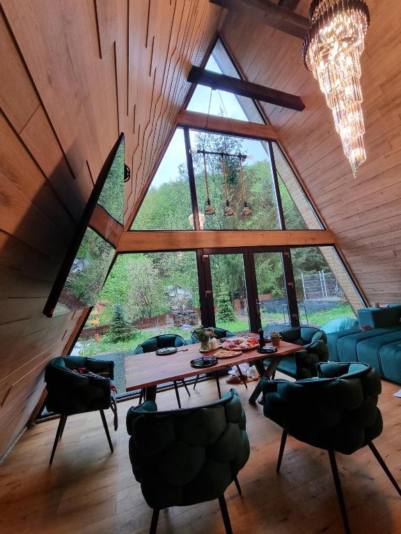 a room with a table and chairs and a large window at Mia A-Frame Chalet Cheia in Cheia