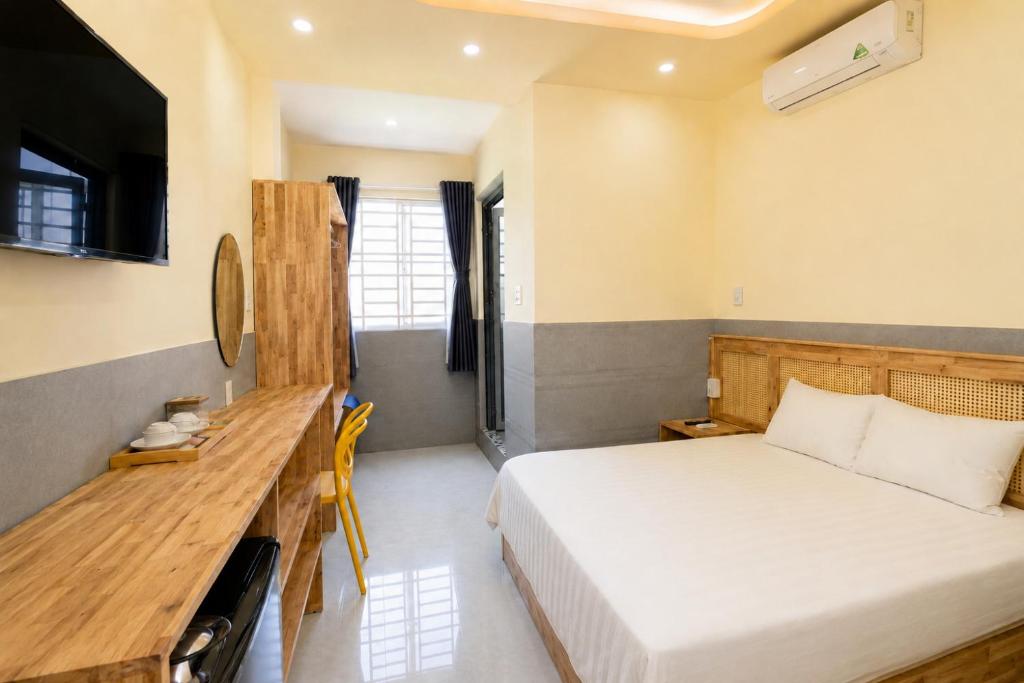 a bedroom with a bed and a desk and a television at De Rivé Homestay - Bến Ninh Kiều in Can Tho