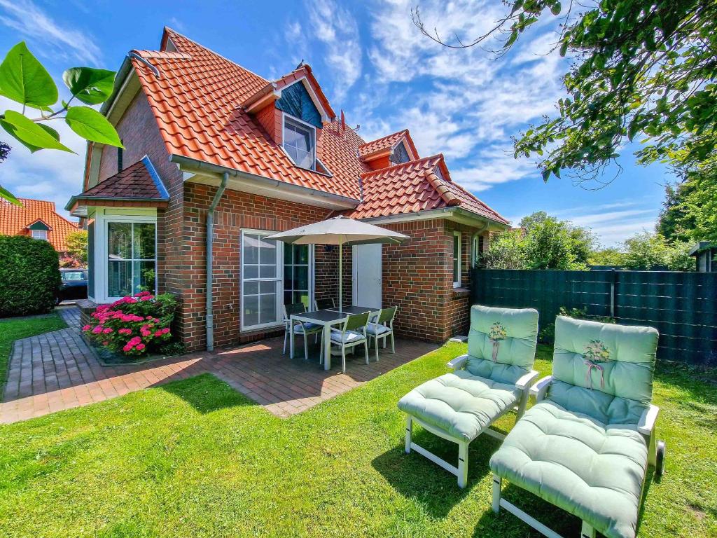 a house with a patio with chairs and an umbrella at Liekedeeler in Greetsiel