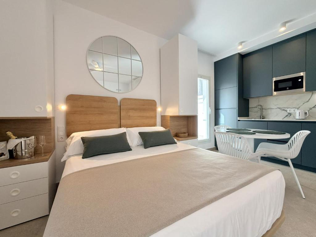a bedroom with a large bed and a kitchen at Villa Julia Apartamentos in Chipiona