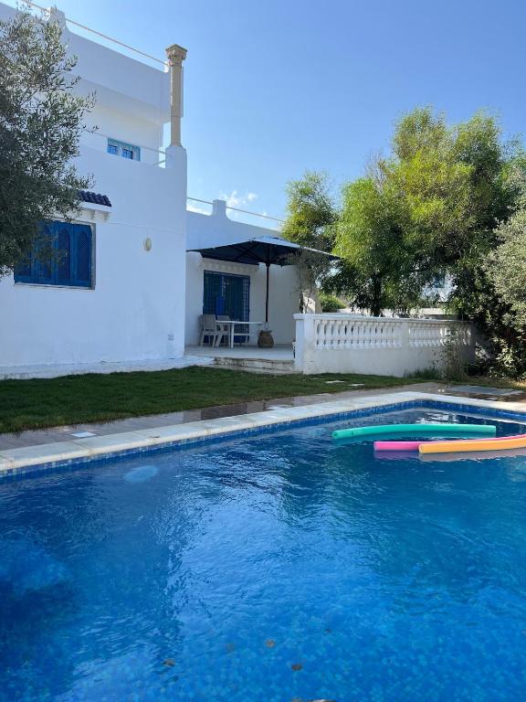 a swimming pool in front of a house at Spacious villa for holidays in Kerkouene