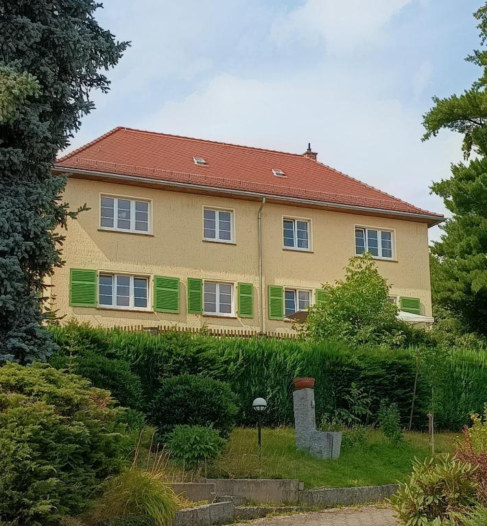 a large yellow house with green shutters on it at Ferienwohnung Finkenberg in Sebnitz
