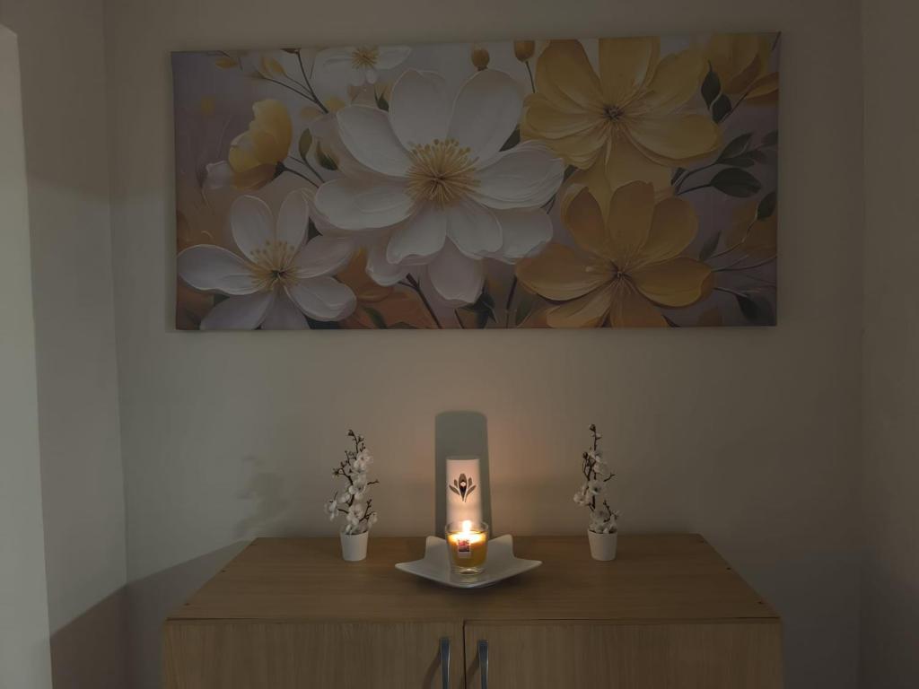 a table with a candle and a painting on the wall at Ketty apartments in Niš
